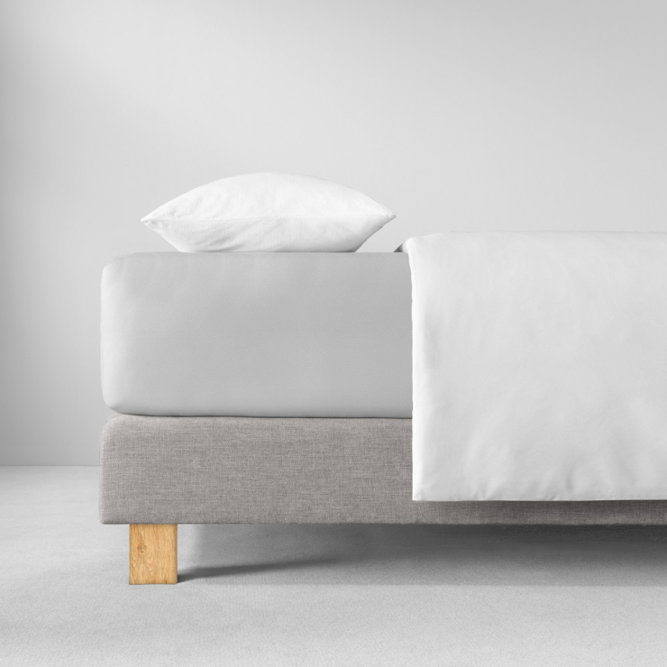 Spannbettlaken in sehr hellen, kühlen Hellgrau auf Bett aufgezogen